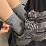 A close-up of grey Heartstrings ribbed crew socks styled with dark grey athletic sneakers.