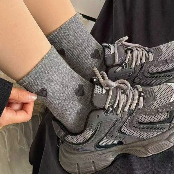 A close-up of grey Heartstrings ribbed crew socks styled with dark grey athletic sneakers.