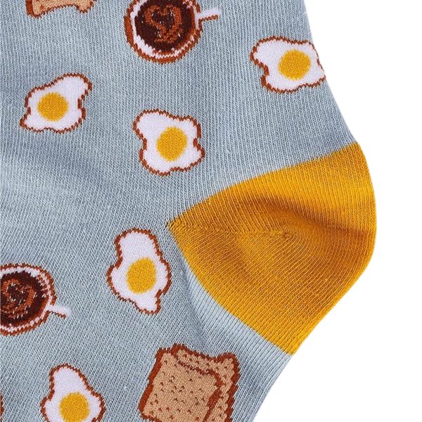 A close-up view of a blue sock featuring a repeating breakfast pattern of fried eggs, toast, and coffee with a solid yellow heel.