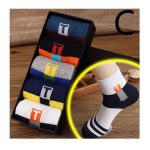 A set of men's in-tube crew socks featuring a "T" letter design, displayed in a gift box next to a model wearing one of the pairs.